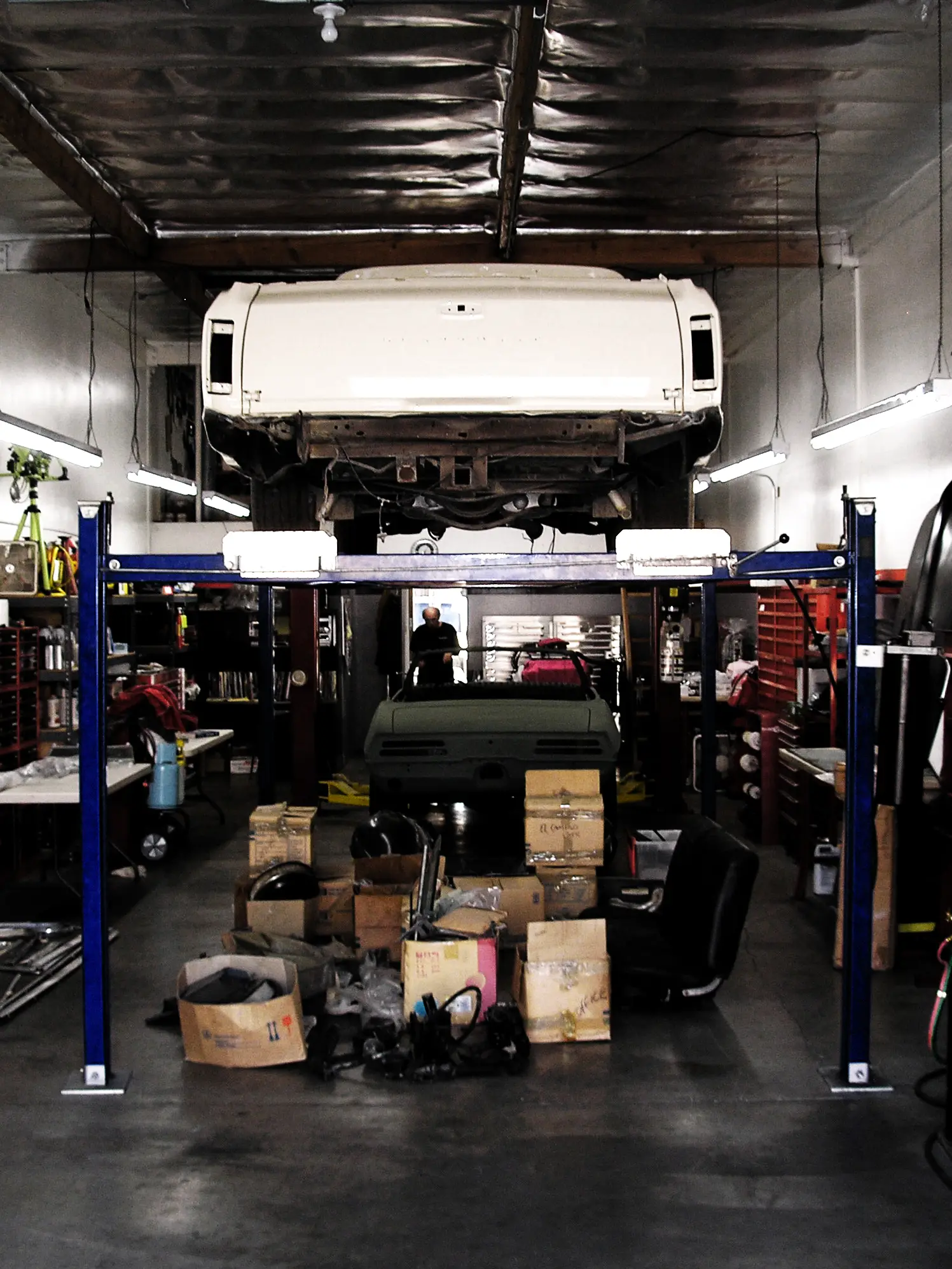 A car raised on a two-post lift in a working repair shop